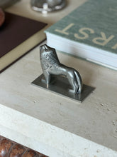 Angled overhead view of the full lion figure on its base plate, next to a green book