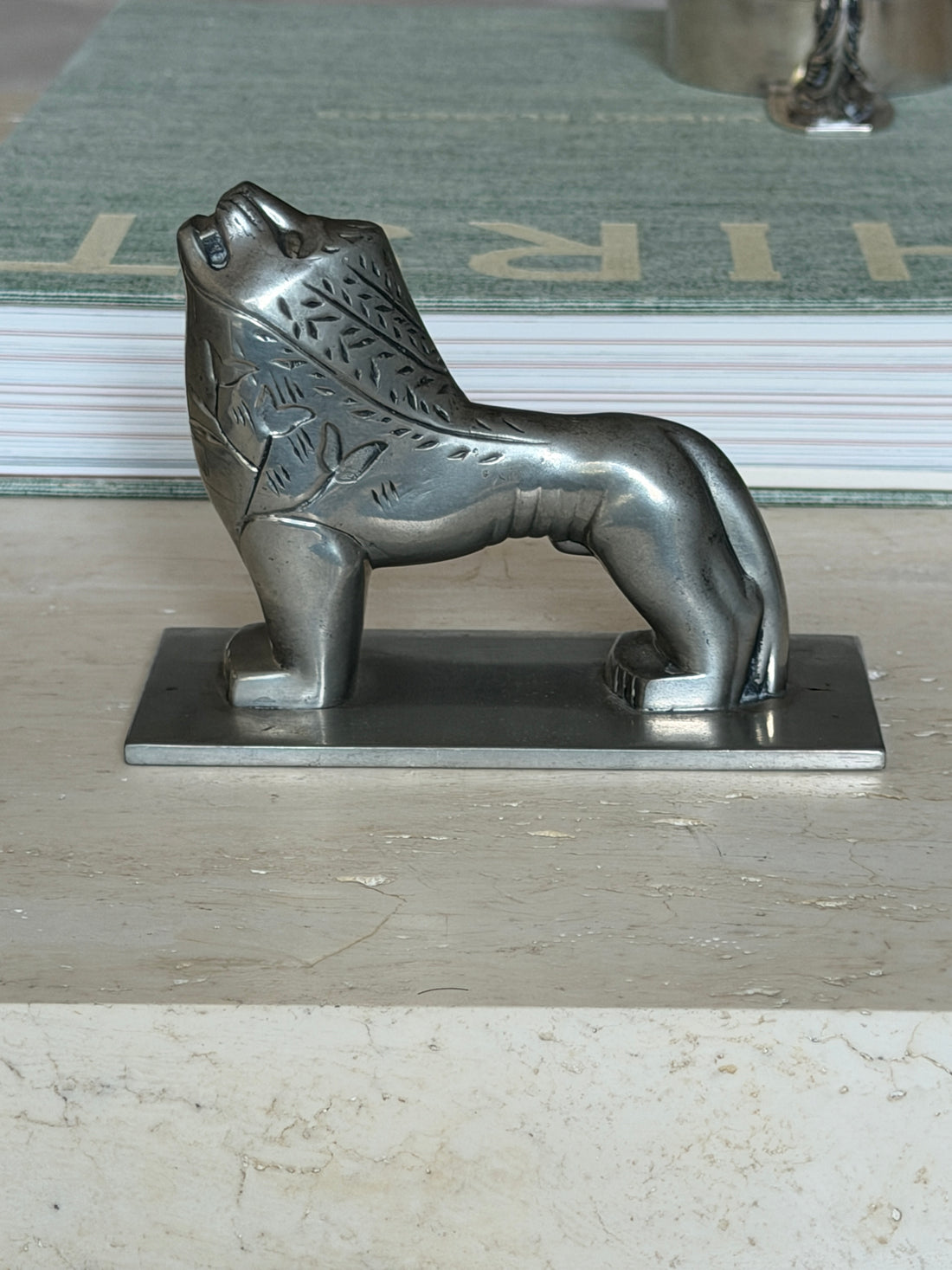Side profile view of the full lion figure resting on a book, head raised