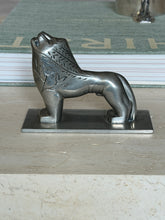 Side profile view of the full lion figure resting on a book, head raised