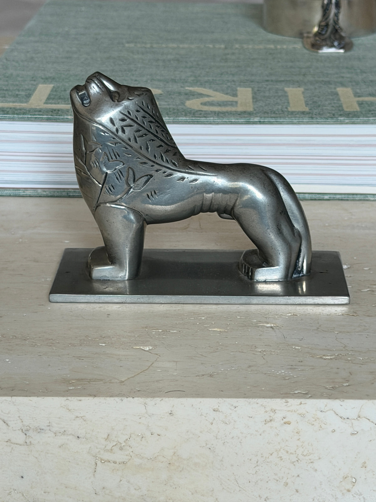 Side profile view of the full lion figure resting on a book, head raised
