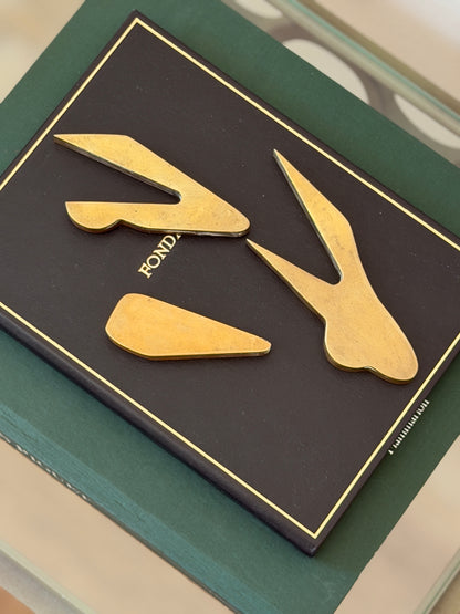 Collectors Gene bronze car paperweight disassembled showing three separate interlocking metal puzzle pieces