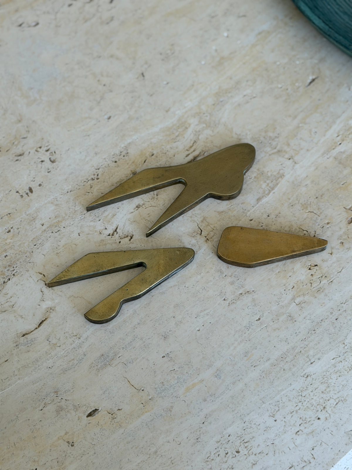 Three disassembled cast bronze interlocking components of Collectors Gene vintage car paperweight on marble table