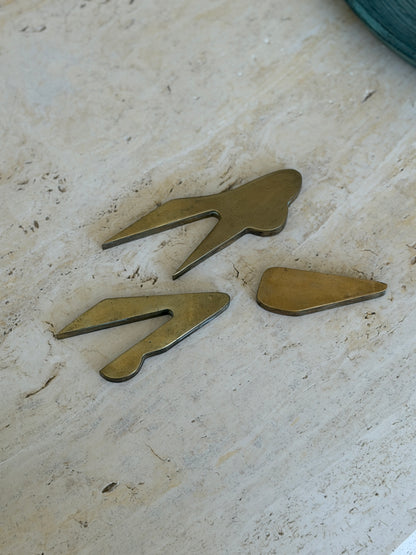 Three disassembled cast bronze interlocking components of Collectors Gene vintage car paperweight on marble table