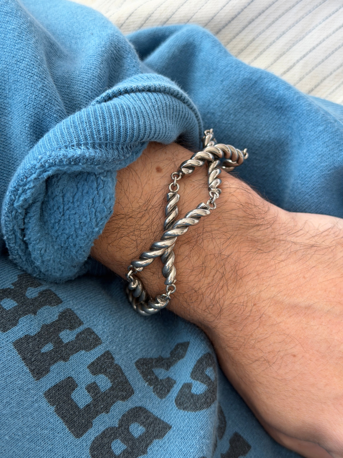 Overhead view of the vintage silver twisted rope bracelet on the wrist, polished highlights contrasting with darker patina in the recesses of each coil