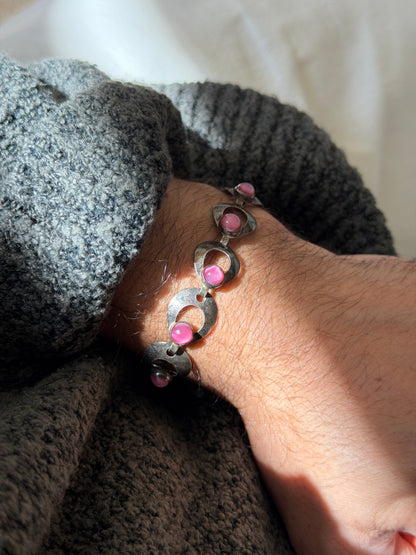 Danish modernist silver bracelet in sunlight, the pink cabochons glowing with a soft chatoyant sheen inside the crescent cutouts