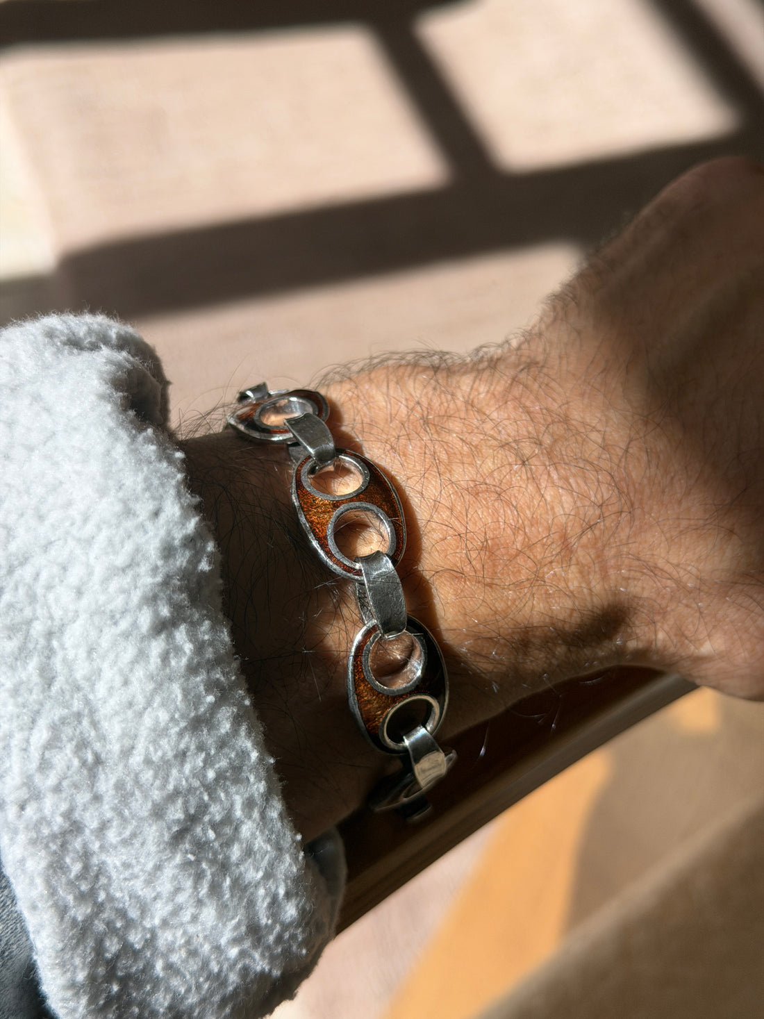 Angled wrist view of the vintage Italian bracelet from Arezzo, the enamel glowing amber brown against polished silver outlines