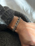 Double oval curb link bracelet on the wrist, the twin silver strands of each link outlined by dark recesses