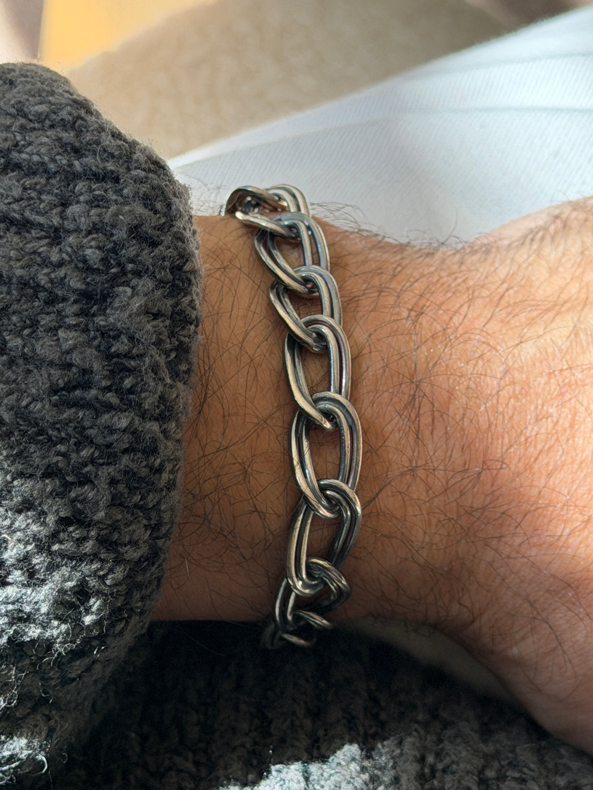 Close view of the double link bracelet on the wrist, the hand formed ovals showing polished highlights and darker patina