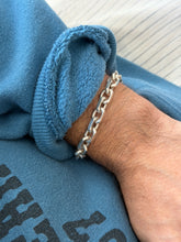 Bracelet worn on the wrist against a ribbed cream top and printed sweatshirt sleeve
