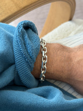 Bracelet draped over the curved edge of a wooden chair arm, hanging loose against a cream carpet