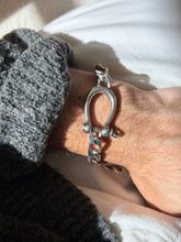 Vintage sterling silver curb chain bracelet with a large horseshoe shaped shackle closed by a screw pin, worn on the wrist in bright sun