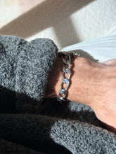 Wrist view of the heavy beveled curb chain section of the bracelet, the shackle pin just visible at the cuff