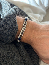 Lapis and silver curb bracelet on the wrist, the deep blue stones flecked with lighter veining between tight polished links