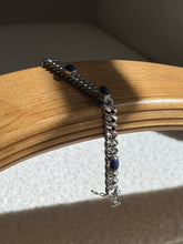 Lapis lazuli and sterling curb bracelet draped over a bentwood oak chair arm, showing three cabochons and the box clasp