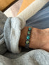 Cuff worn on the wrist over a grey sweatshirt cuff, showing the four turquoise stones and stamped silver design