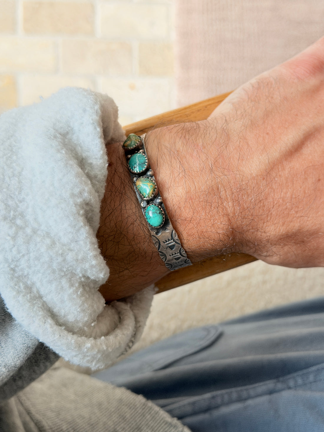 Cuff worn on the wrist against a tiled brick wall background