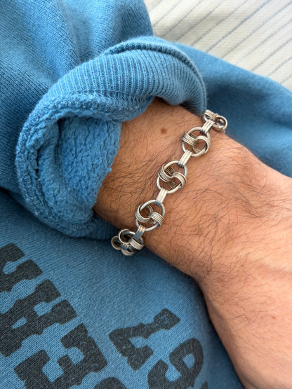 Bracelet worn on the wrist against a printed sweatshirt and cream carpet