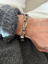 Vintage sterling silver nautical rope link bracelet of elongated teardrop loops bound with coiled wire wraps, worn on the wrist against a gray knit cuff