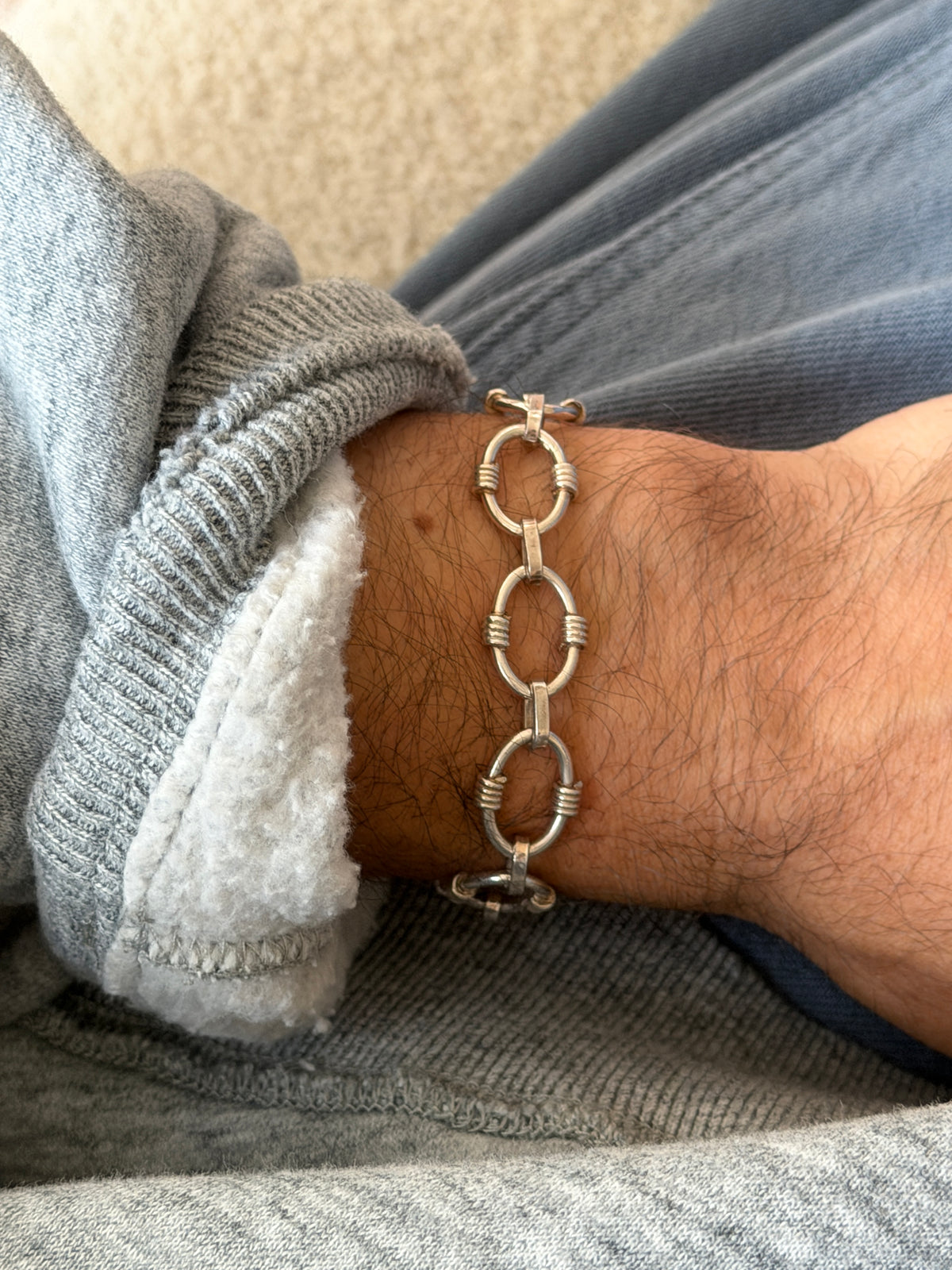 Wrist shot detail of the ribbed link pattern on the silver bracelet