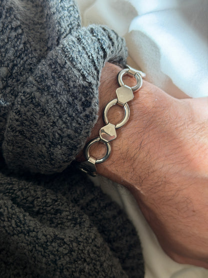 Vintage sterling silver bracelet of open round rings joined by flat hexagonal plates, worn on the wrist against a gray knit cuff