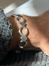 Close wrist view of the sterling round link bracelet, light surface wear visible on the flat hexagonal plates and hinged joints