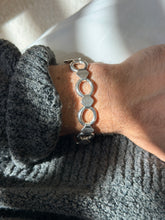 Straight on wrist view of the round and band bracelet, the bright silver rings and hexagon bands in raking light