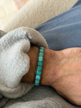 Cuff worn on the wrist over a grey sweatshirt cuff, with blue jeans in the background