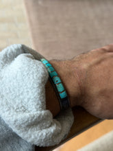 Cuff worn on the wrist against a tiled brick wall background, showing the small clasp