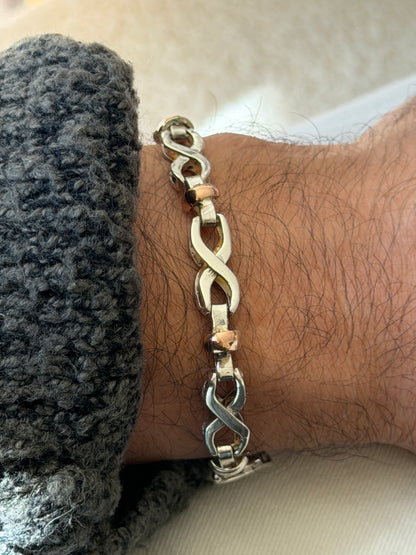 Close wrist view of the infinity bracelet, the sculpted silver figure eights and the polished gold rondelle between them